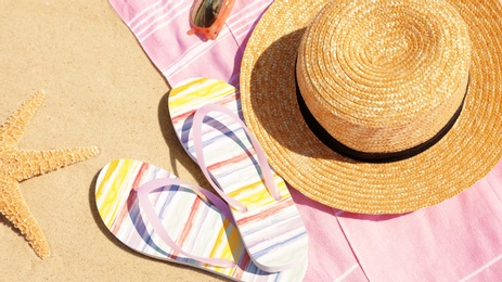 Photo of Stylish beach accessories on sandy beach, closeup