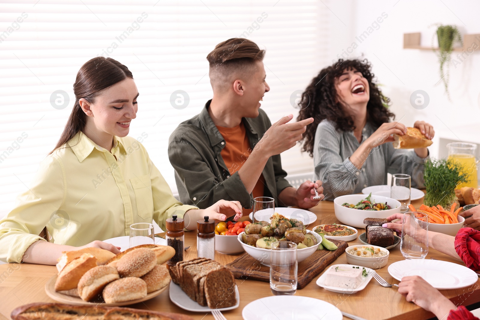 Photo of Friends eating vegetarian food at wooden table indoors