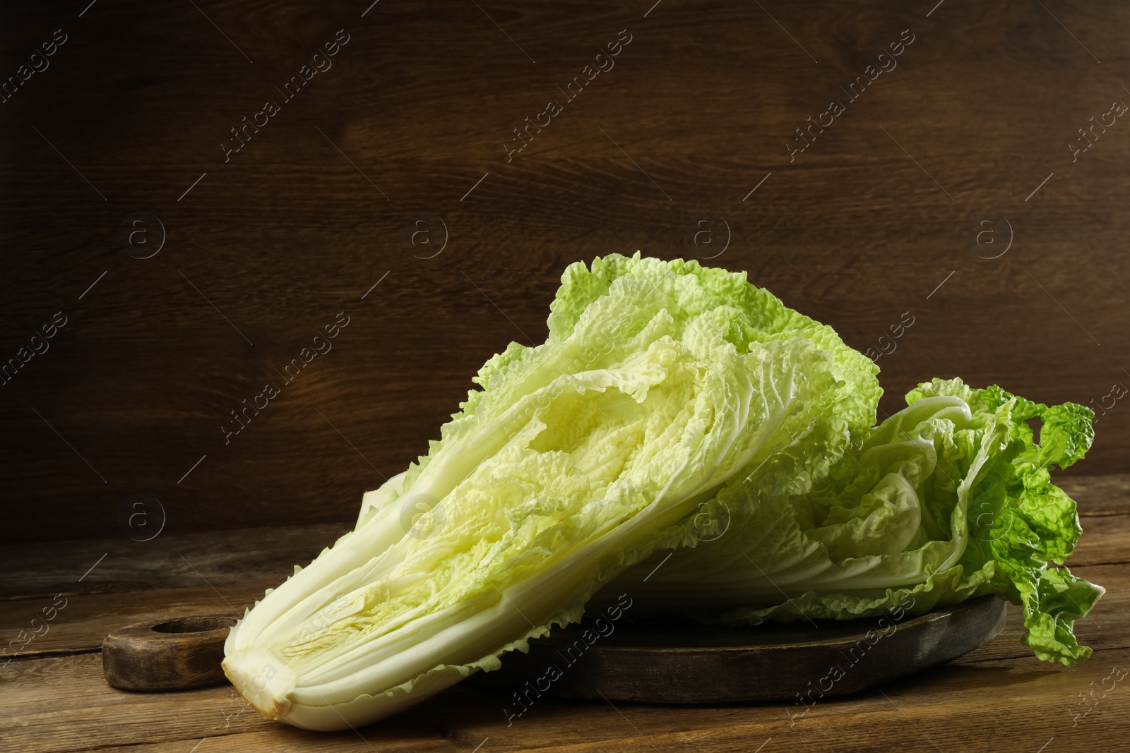 Photo of Halves of fresh ripe Chinese cabbage on wooden table