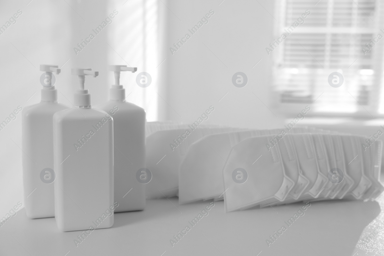 Photo of Hand sanitizers and respiratory masks on white table indoors. Protective essentials during COVID-19 pandemic