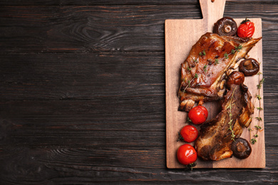 Photo of Delicious roasted ribs served on black wooden table, top view. Space for text