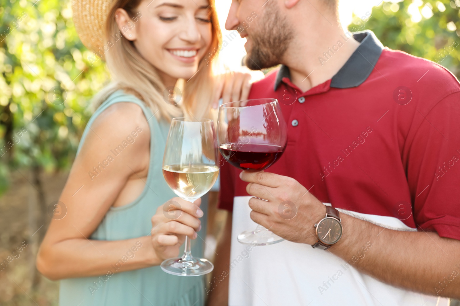 Photo of Romantic couple holding glasses of wine and having fun at vineyard