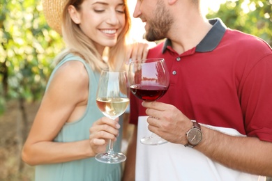 Photo of Romantic couple holding glasses of wine and having fun at vineyard