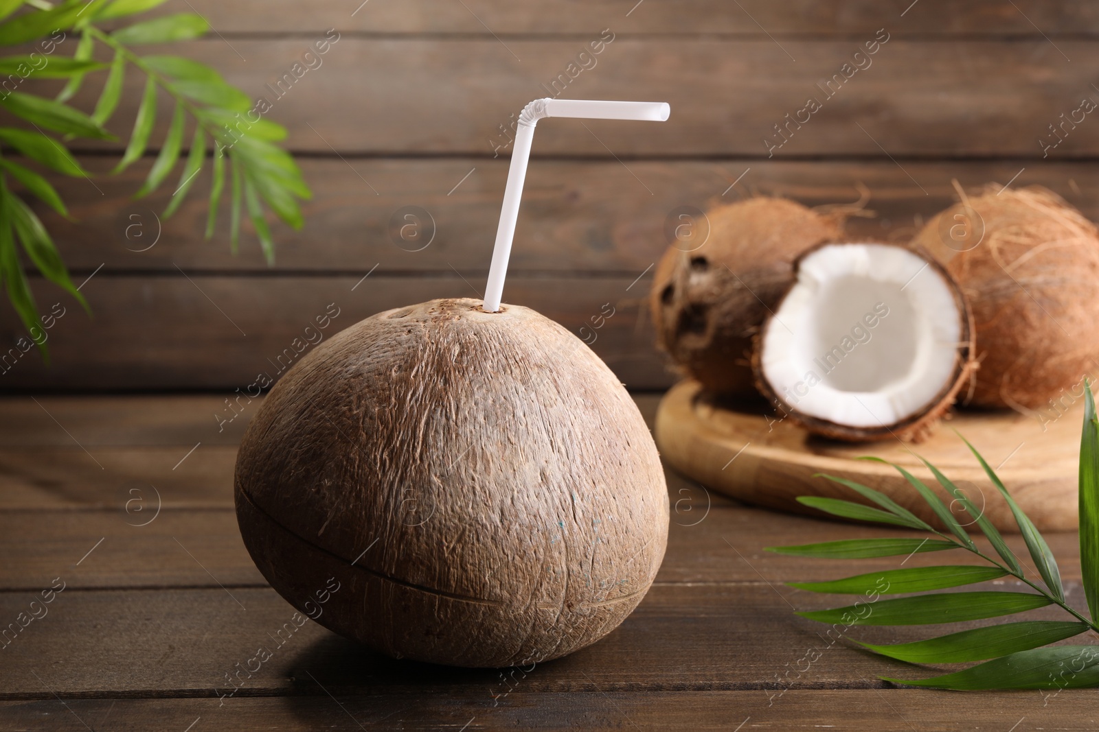 Photo of Coconut water. Fresh nut with straw on wooden table