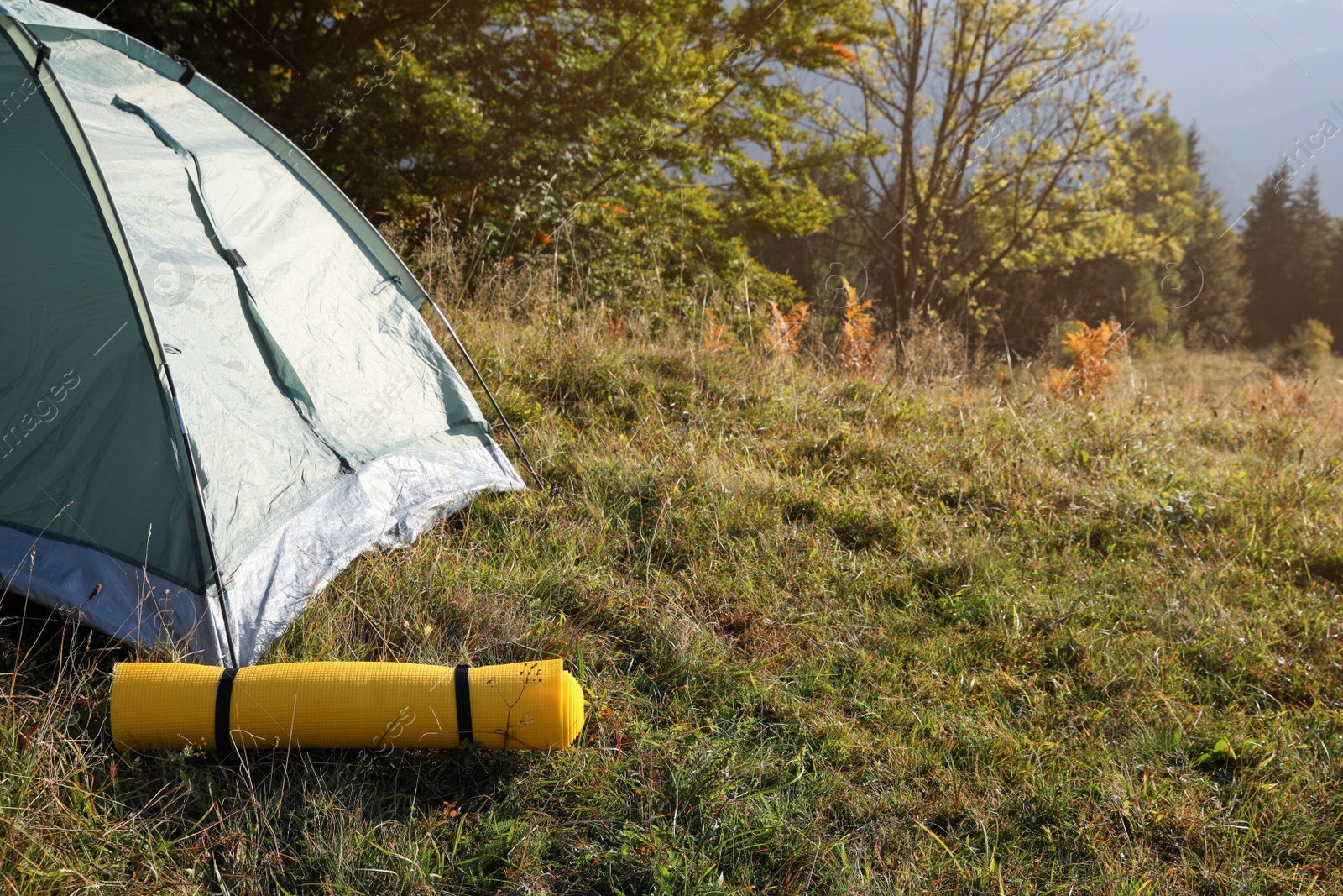 Photo of Sleeping mat near camping tent outdoors. Tourism equipment