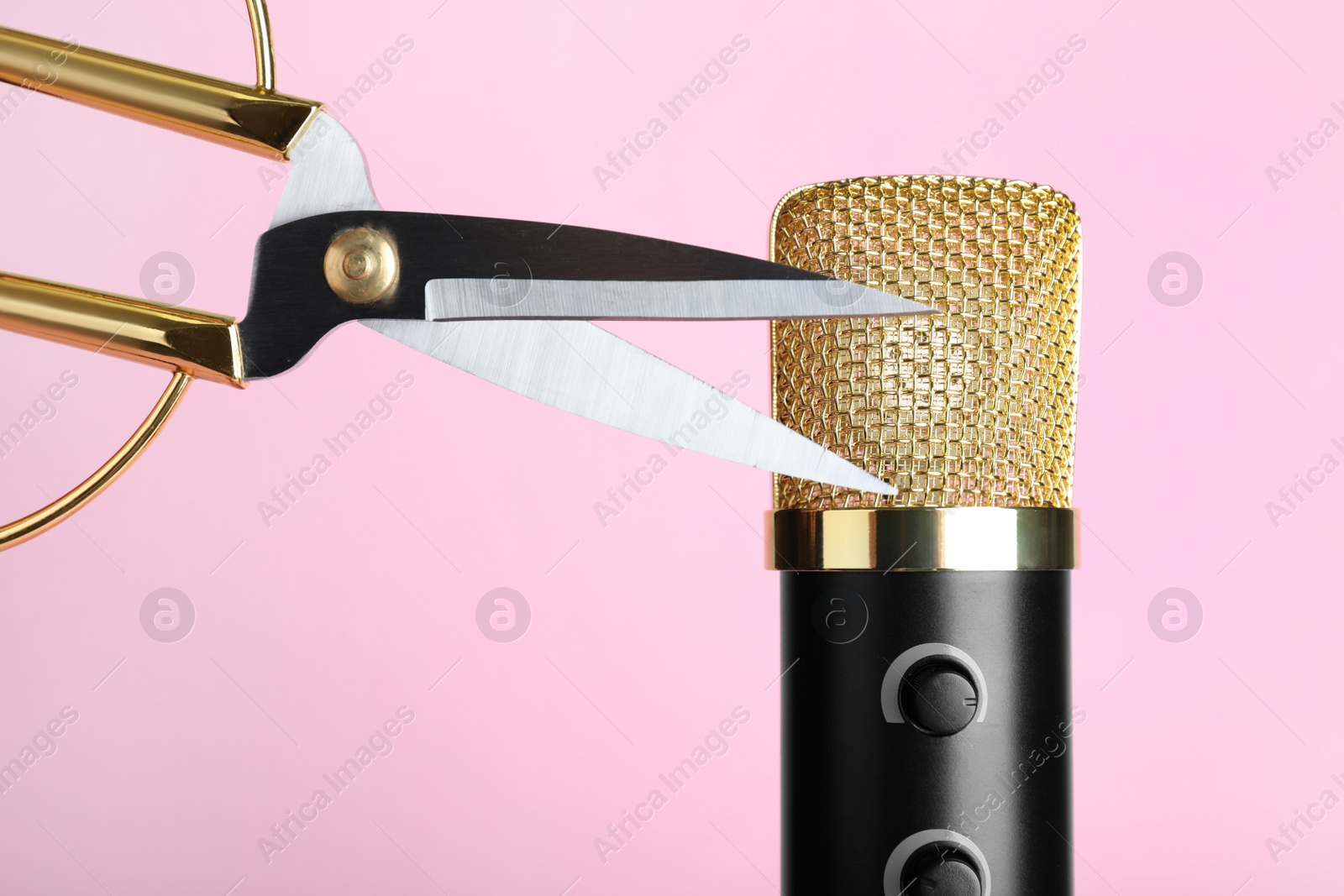 Photo of Making ASMR sounds with microphone and scissors on pink background, closeup