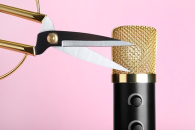 Photo of Making ASMR sounds with microphone and scissors on pink background, closeup