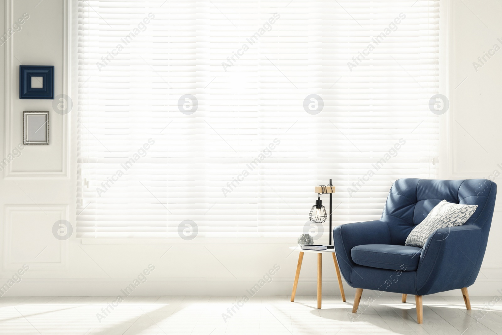 Photo of Comfortable armchair with pillow, stool and lamp near big window in spacious room. Interior design