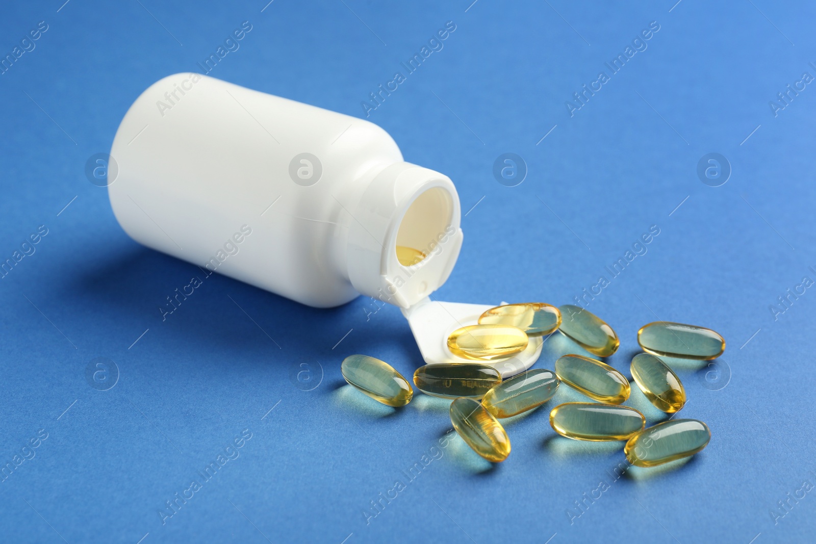 Photo of Bottle of vitamin capsules on blue background