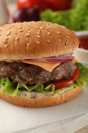 Photo of Tasty hamburger with patty, cheese and vegetables on light table, closeup