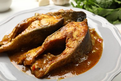 Photo of Tasty fish curry on white table, closeup. Indian cuisine