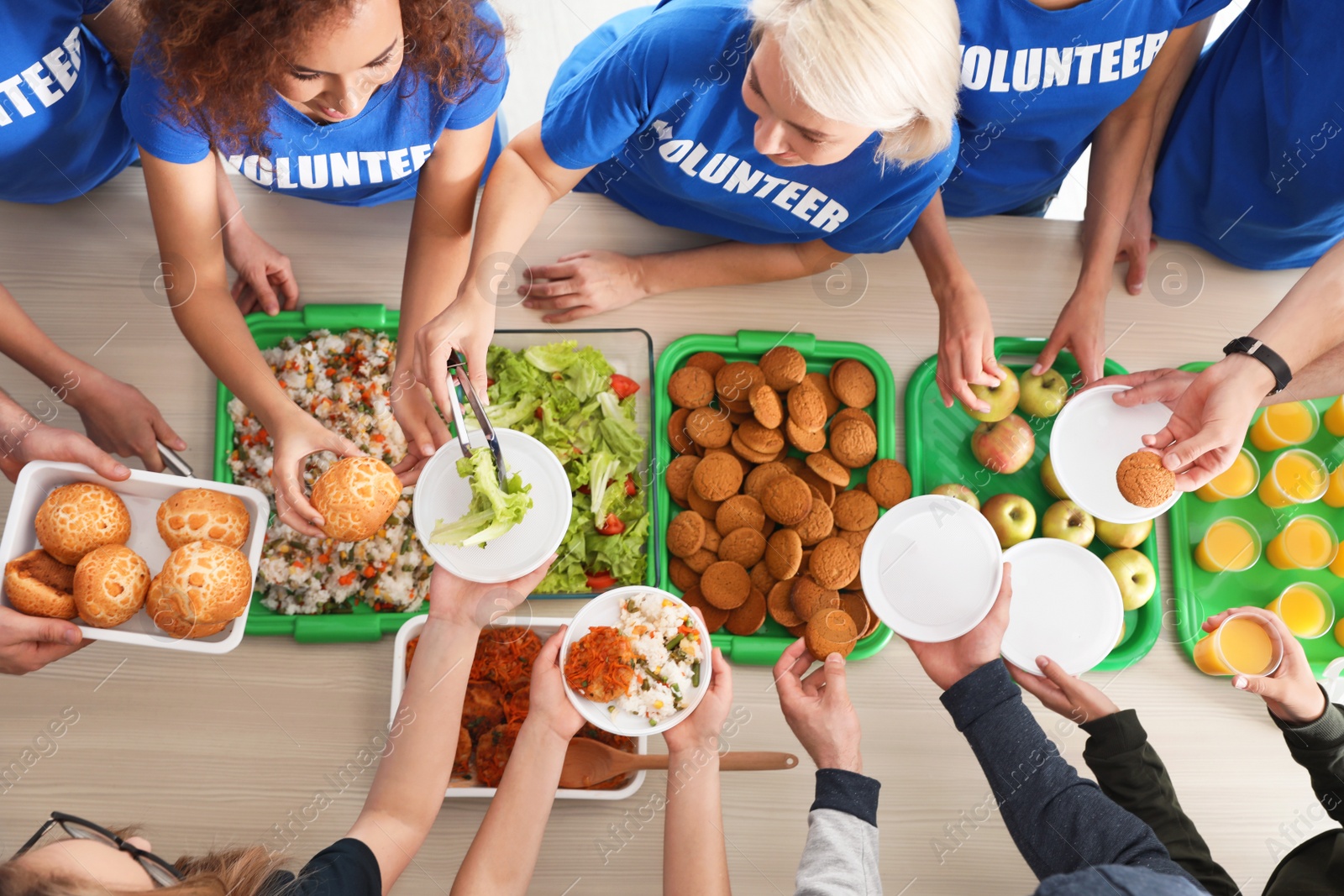 Photo of Volunteers serving food to poor people at table, top view