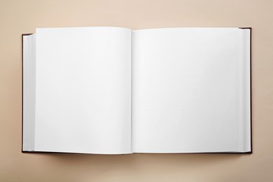 Photo of Open photo album on beige background, top view. Space for text