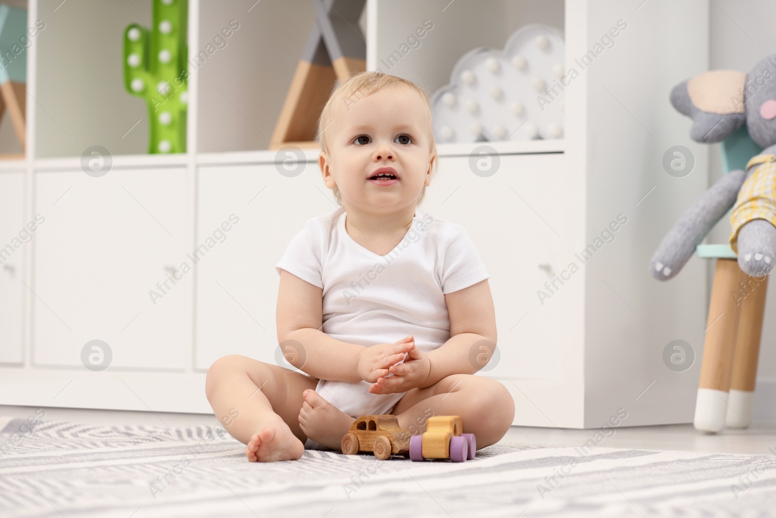 Photo of Children toys. Cute little boy playing with wooden cars on rug at home