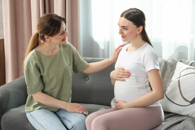Doula taking care of pregnant woman on sofa at home. Preparation for child birth