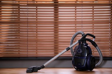 Modern vacuum cleaner near window indoors, space for text