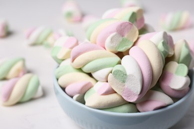 Photo of Bowl with colorful marshmallows on white table, closeup