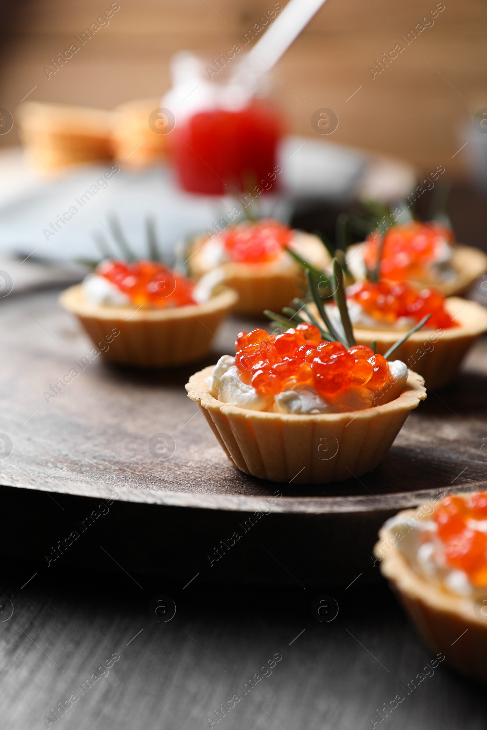 Photo of Delicious tartlets with red caviar and cream cheese served on wooden table, closeup