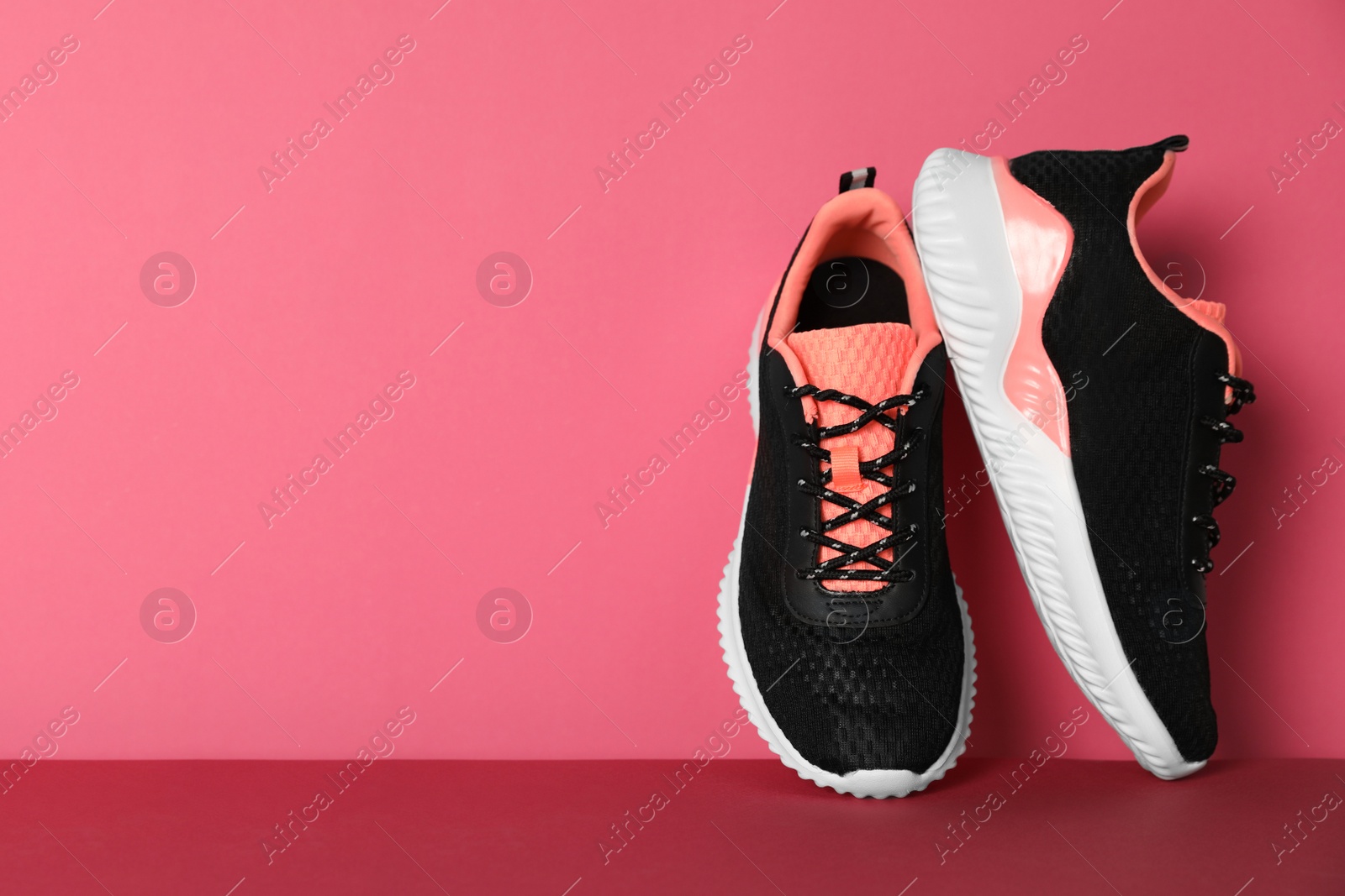 Photo of Pair of stylish sport shoes on pink background, space for text