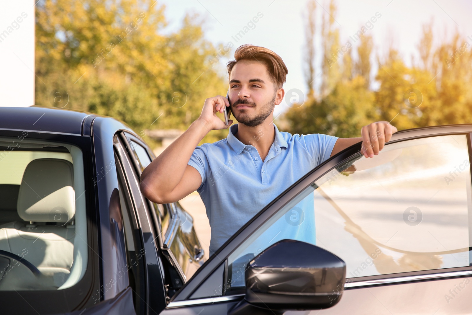 Photo of Young man talking on phone near modern car, outdoors