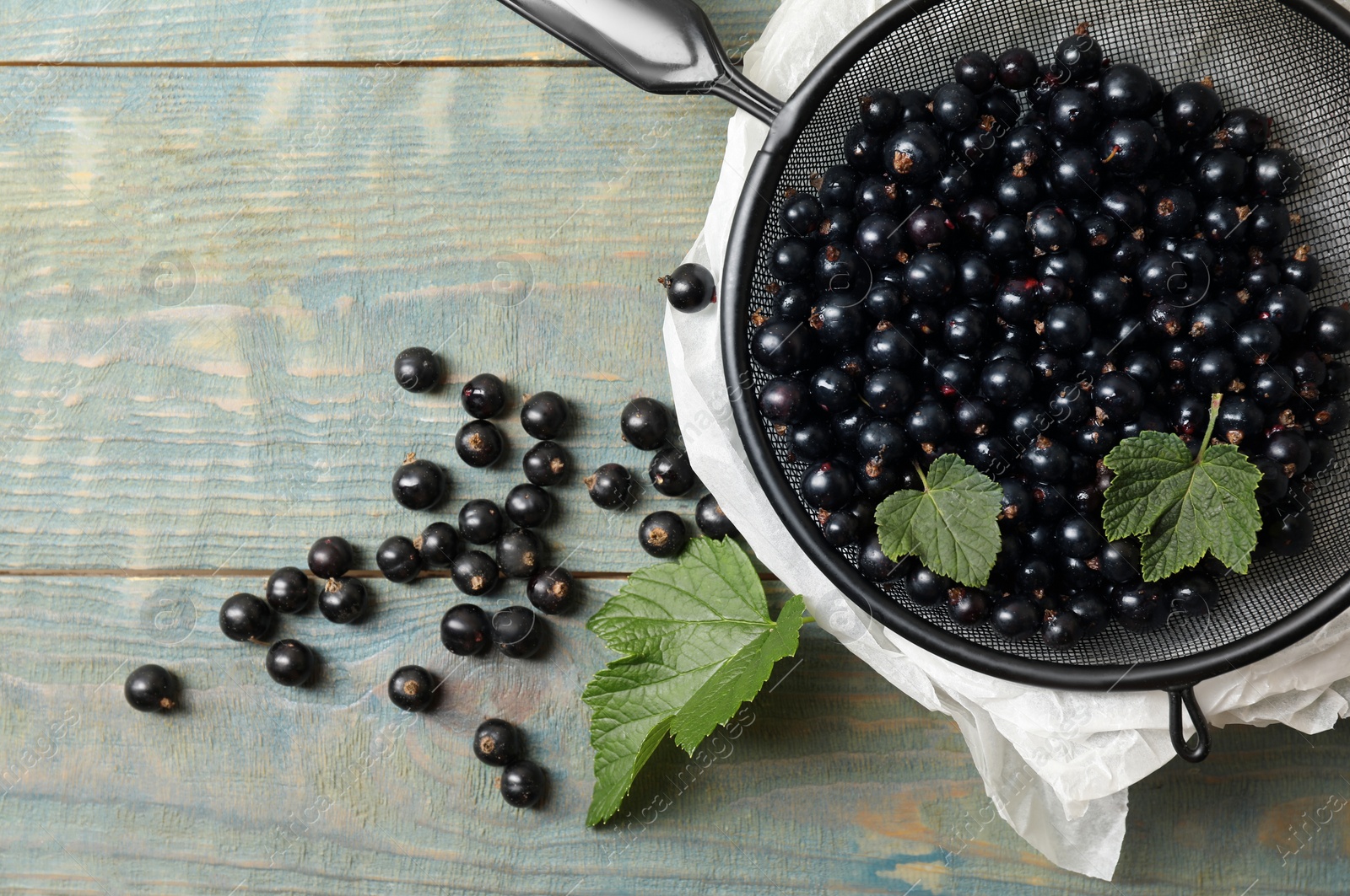 Photo of Ripe blackcurrants and leaves on wooden rustic table, flat lay. Space for text