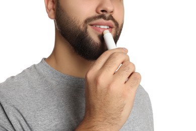 Photo of Young man applying lip balm on white background, closeup