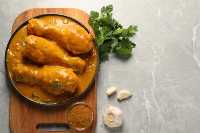 Photo of Tasty chicken curry and ingredients on grey textured table, flat lay. Space for text