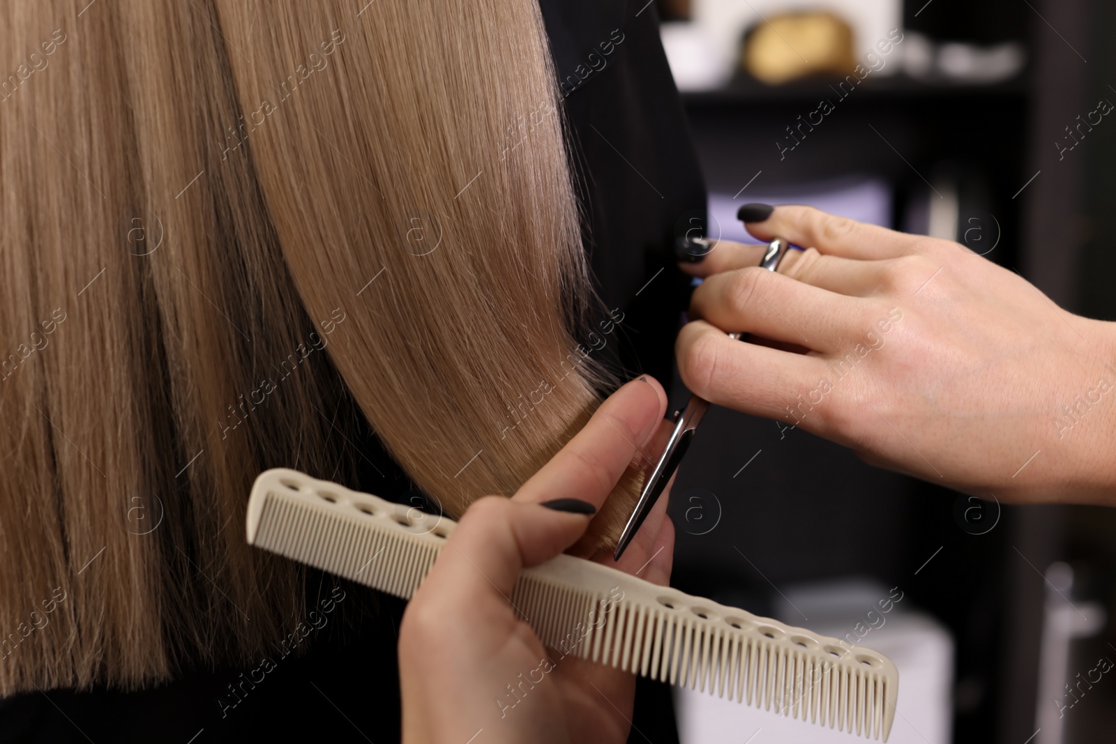 Photo of Professional hairdresser cutting woman's hair in salon, closeup