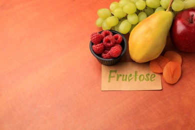 Photo of Card with word Fructose, delicious ripe fruits, raspberries and dried apricots on wooden table, space for text