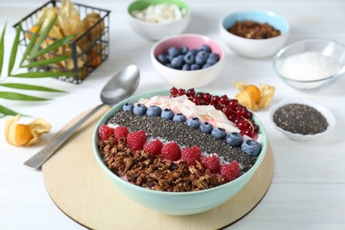 Photo of Tasty smoothie bowl with fresh berries and granola served on white table