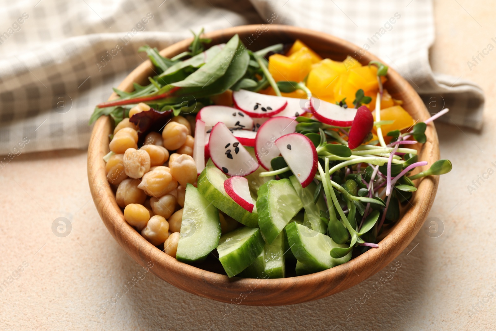 Photo of Delicious vegan bowl with cucumbers, chickpeas and radish on beige table, closeup