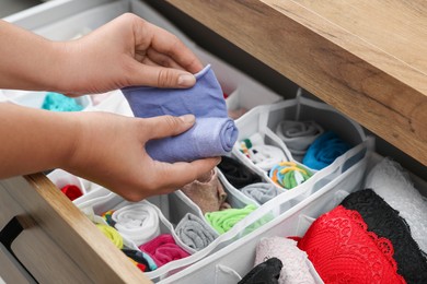 Photo of Woman rolling socks above organizers with underwear in drawer, closeup