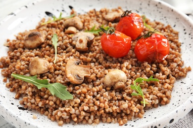 Tasty buckwheat porridge with mushrooms and tomatoes, closeup