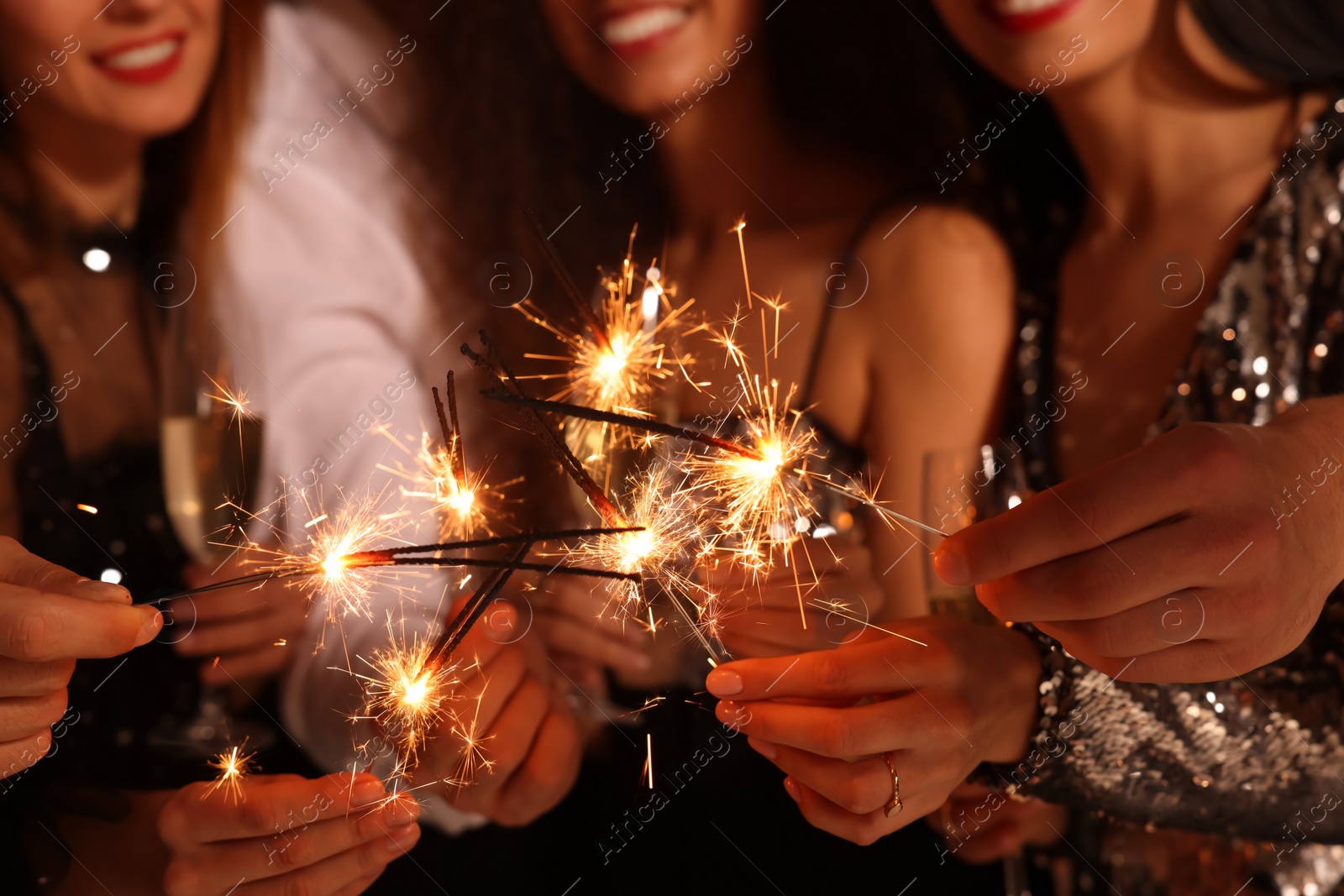 Photo of Friends with glasses of sparkling wine and sparklers celebrating New Year, closeup