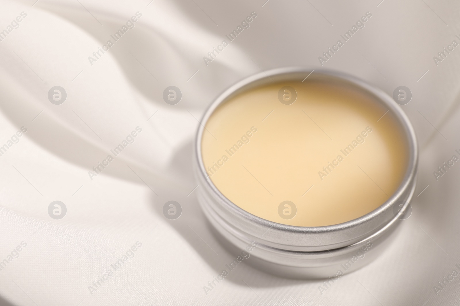 Photo of Lip balm on white fabric, closeup. Space for text