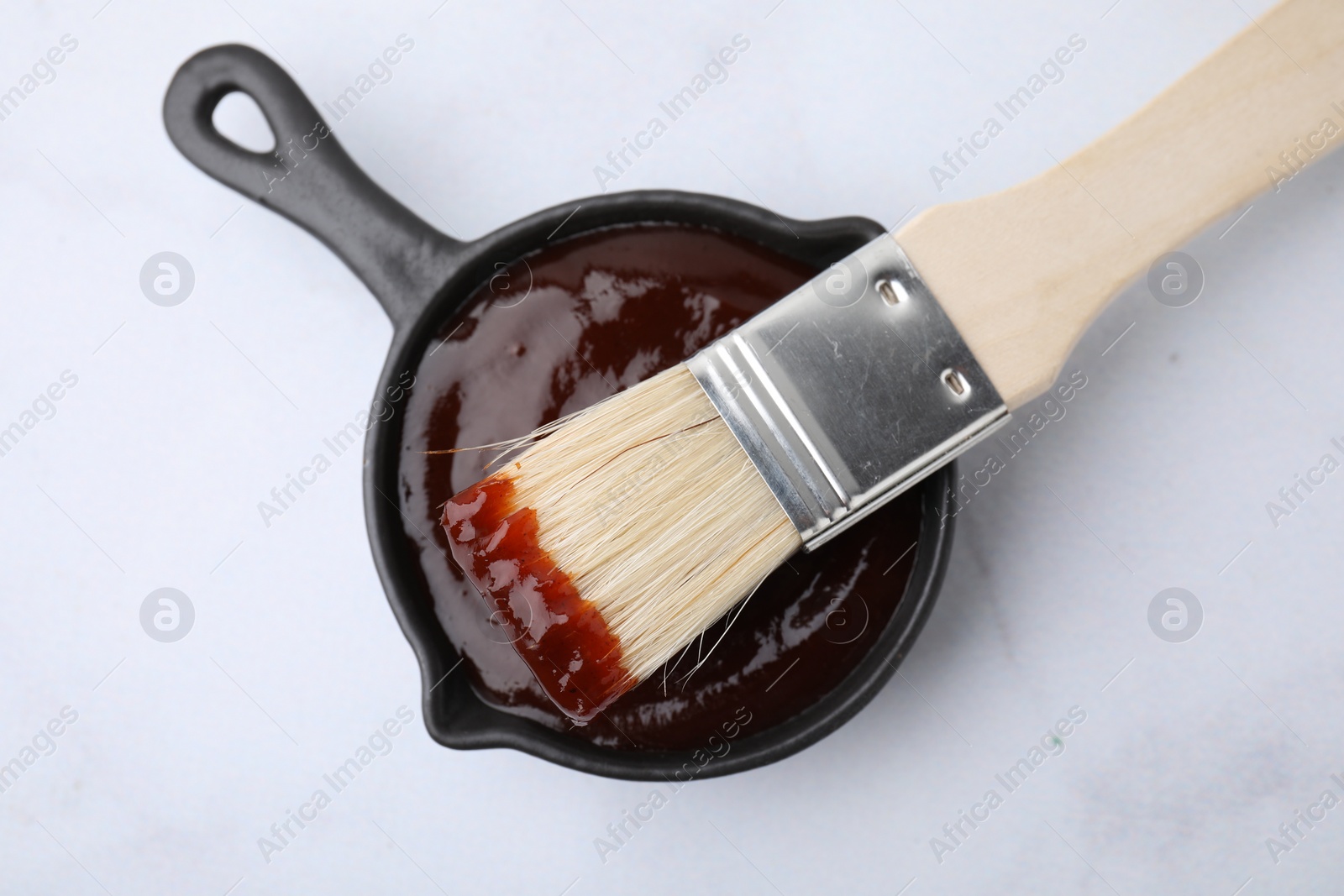 Photo of Marinade in gravy boat and basting brush on white table, top view