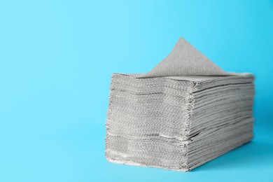 Photo of Stack of paper towels on light blue background, space for text