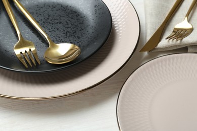 Photo of Stylish ceramic plates and cutlery on white wooden table, closeup
