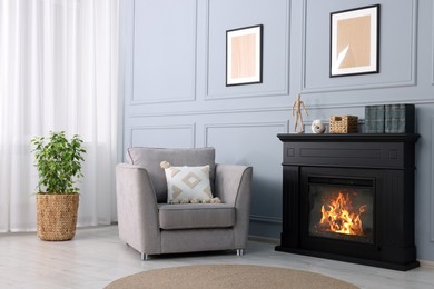 Black stylish fireplace near potted plant and armchair in cosy living room