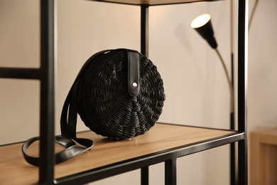 Photo of Elegant black bag on shelf in luxury boutique