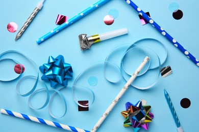Photo of Party blower and festive decor on light blue background, flat lay