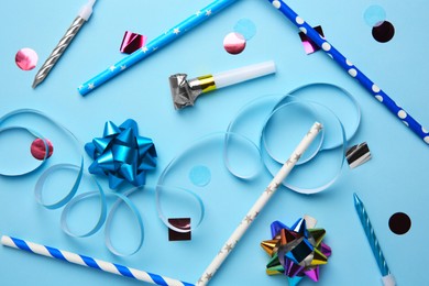 Party blower and festive decor on light blue background, flat lay