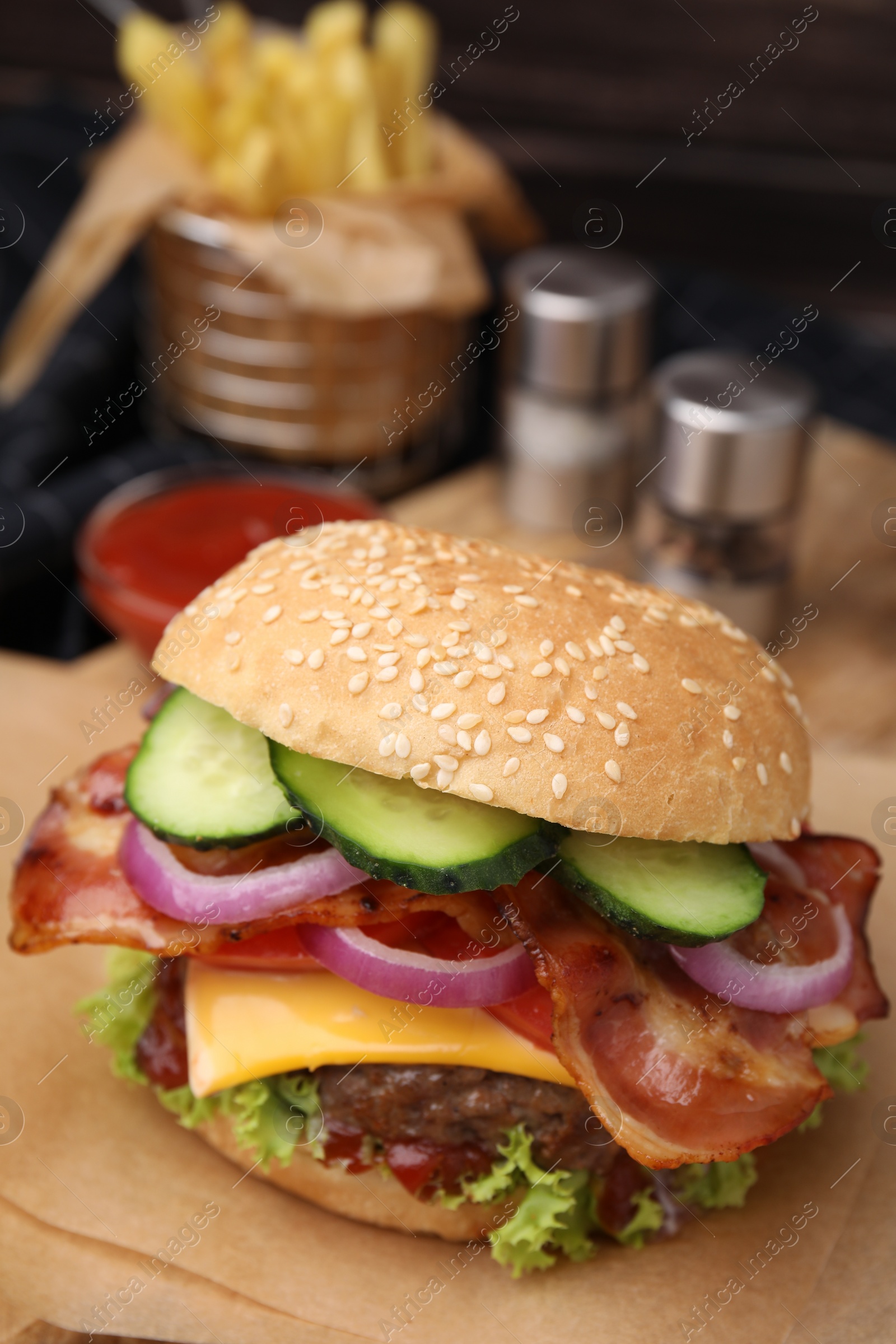 Photo of Tasty burger with bacon, vegetables and patty on wooden board, closeup