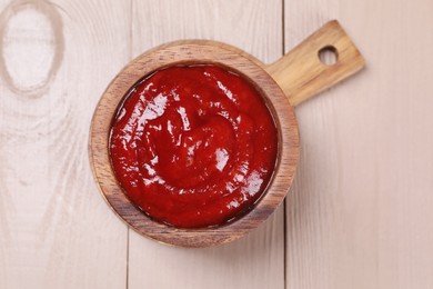 Photo of Delicious ketchup in bowl on light wooden table, top view. Tomato sauce