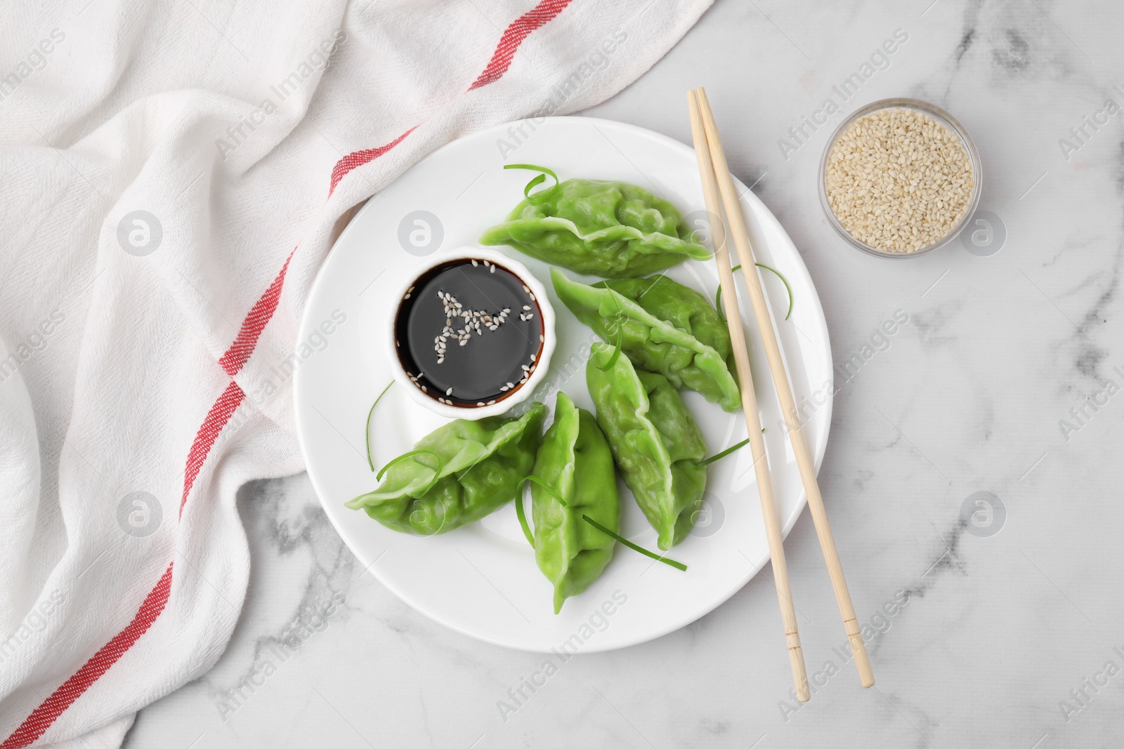 Photo of Delicious green dumplings (gyozas) and soy sauce served on white marble table, flat lay