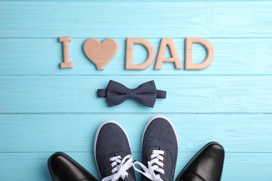 Photo of Flat lay composition with shoes, bow tie and phrase I LOVE DAD on wooden background. Father's day celebration