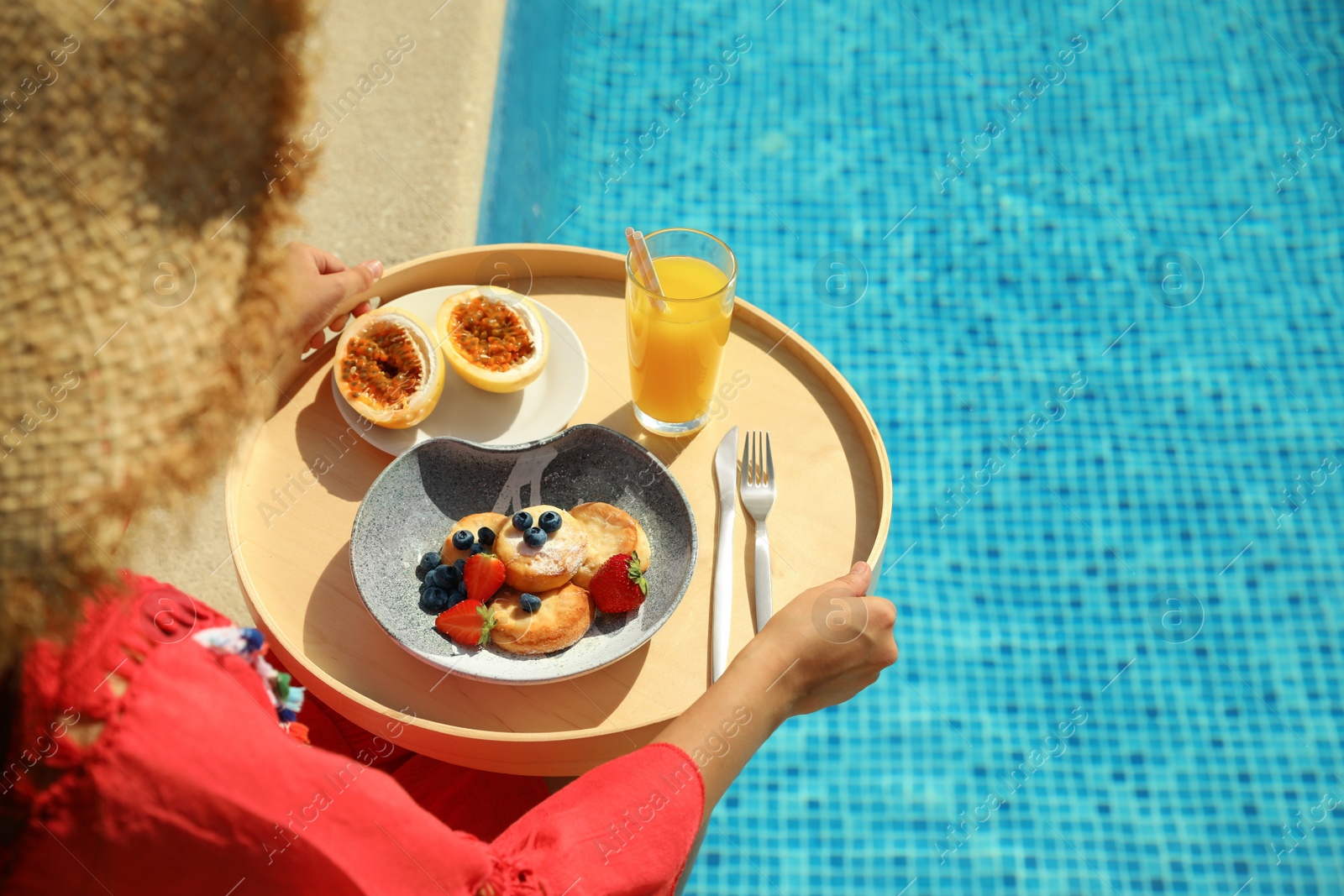 Photo of Young woman with delicious breakfast on tray near swimming pool, closeup