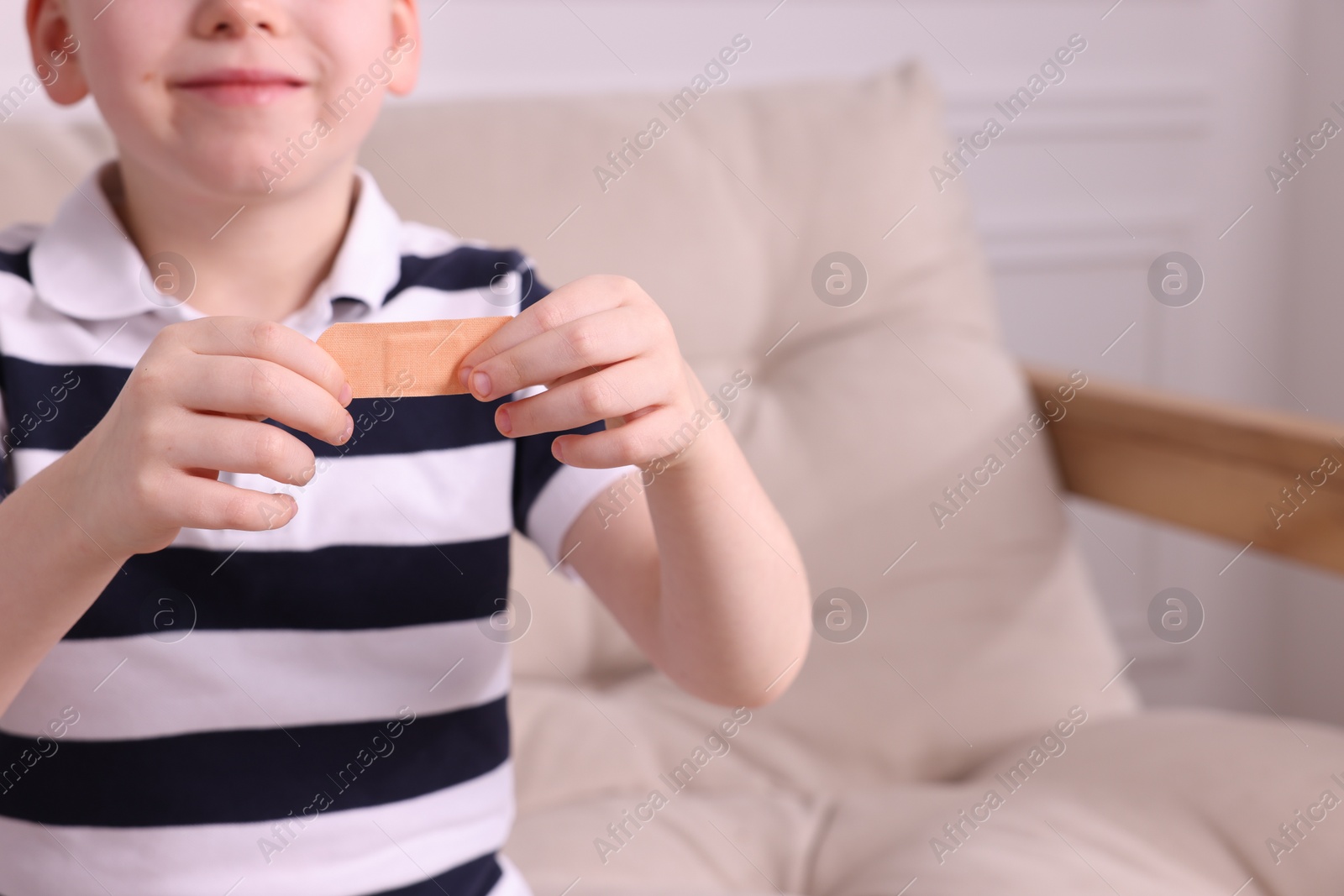 Photo of Little boy with sticking tape on sofa, closeup. Space for text