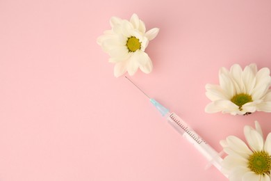 Photo of Medical syringe and chrysanthemum flowers on pink background, flat lay. Space for text