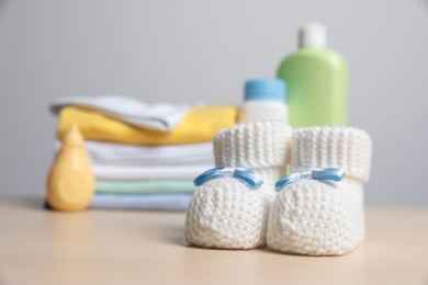 Photo of Baby booties, clothes and accessories on wooden table. Space for text